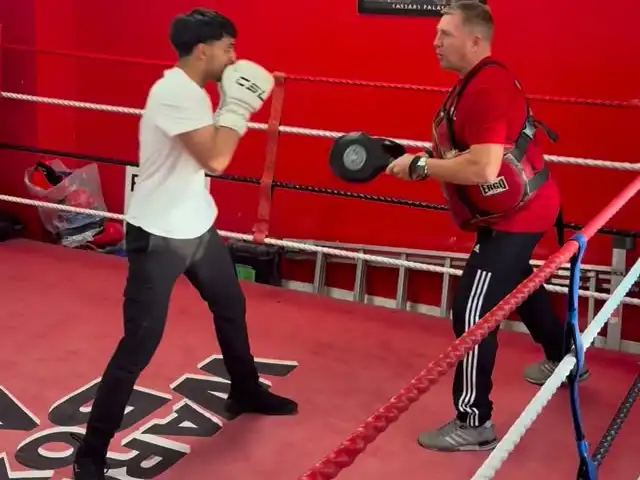 Scott Walker holding pads for a client in the ring at Warriors Boxing Academy